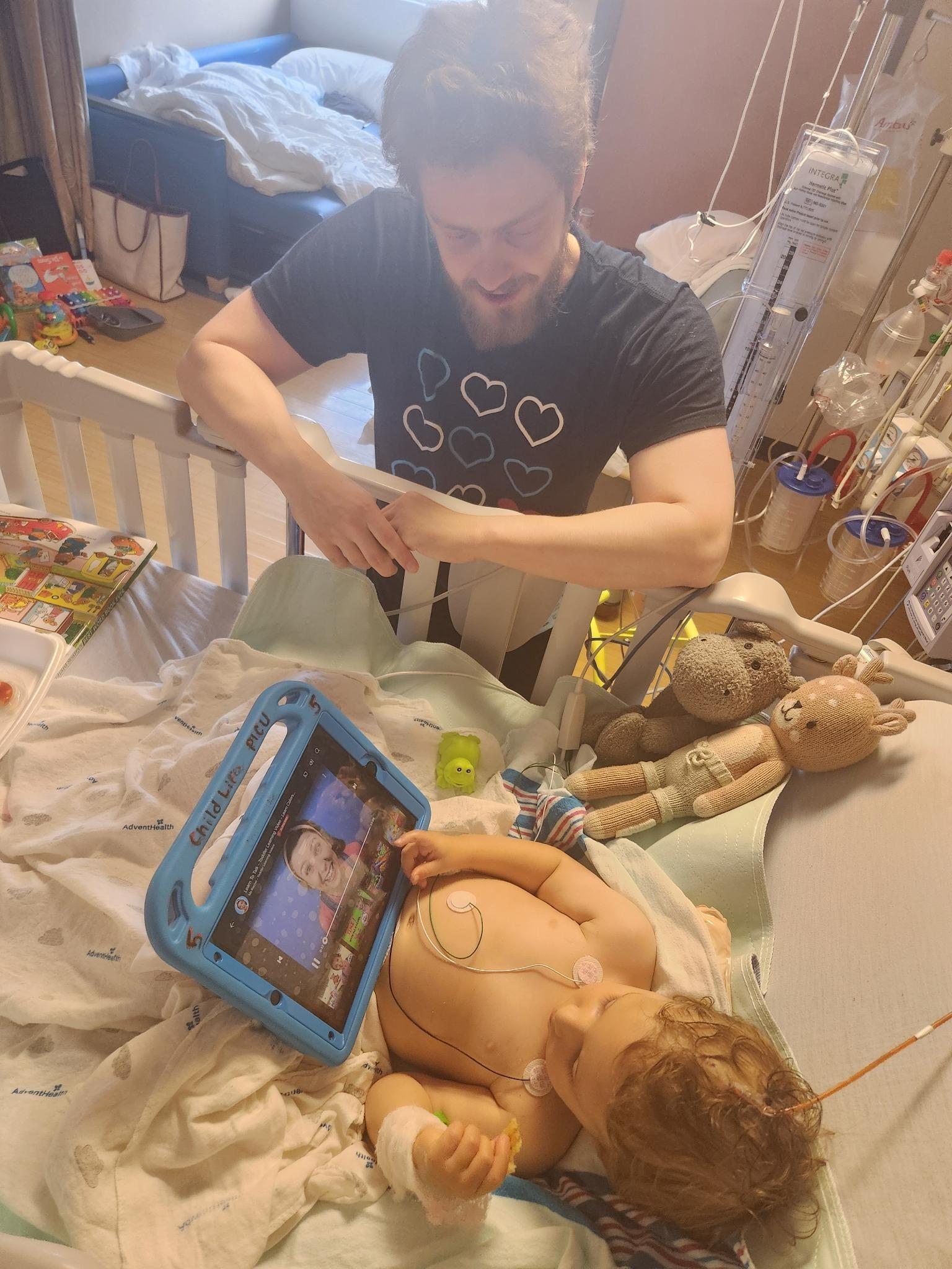 Max in a hospital bed with a tablet with Sam next to him